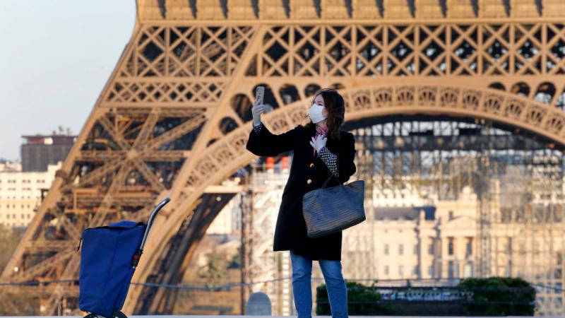 Woman takes selfie in front of Eiffel Tower in March 2020