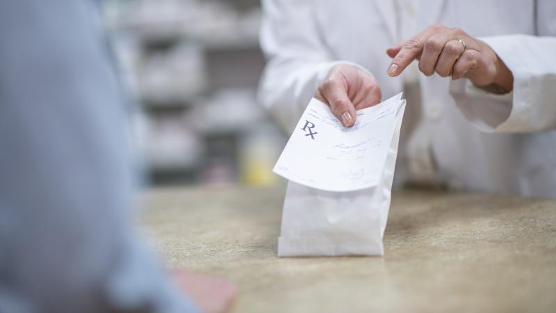 A pharmacist holding out a prescription
