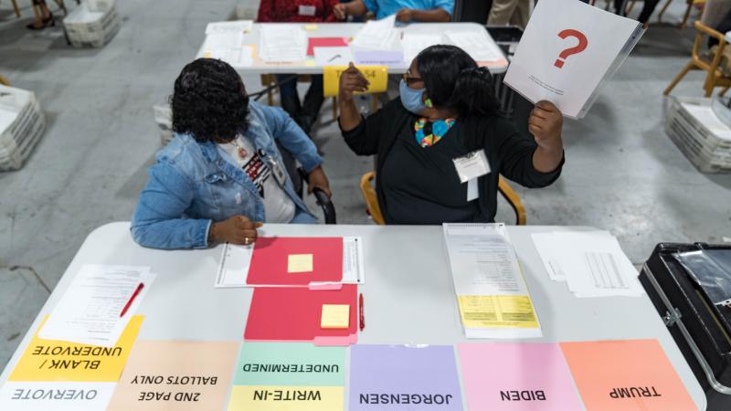 Two Gwinnett county workers raise a card that lets the officials know they have a question as they begin their recount of the ballots on November 13, 2020 in Lawrenceville, Georgia.