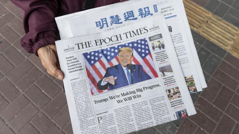 HONG KONG, CHINA - 2020/11/14: A woman distributes the multi-language newspapers The Epoch Times newspaper featuring on its front cover the former US President Donald J. Trump in Hong Kong. 