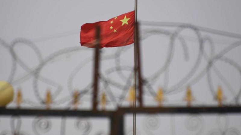Chinese flag behind razor wire at a housing compound in China