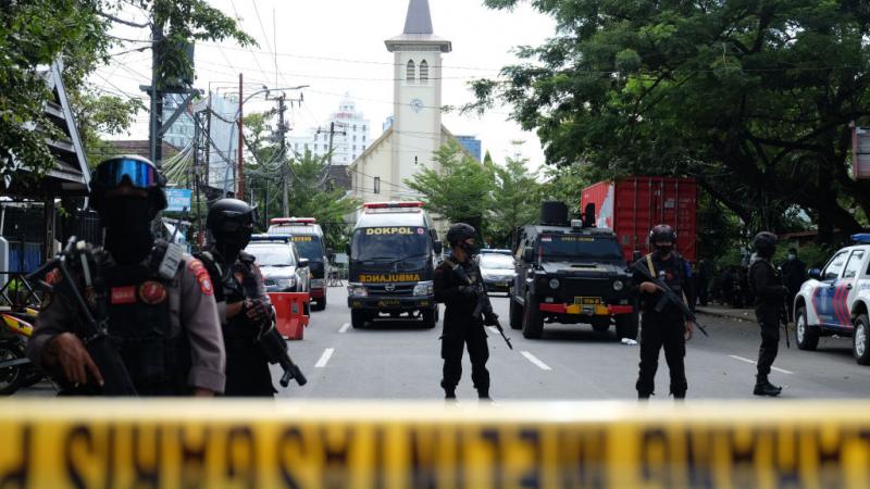 Police officers stand guard in front of Sacred Heart of Jesus Cathedral in Indonesia after a suicide bombing attack on March 28, 2021