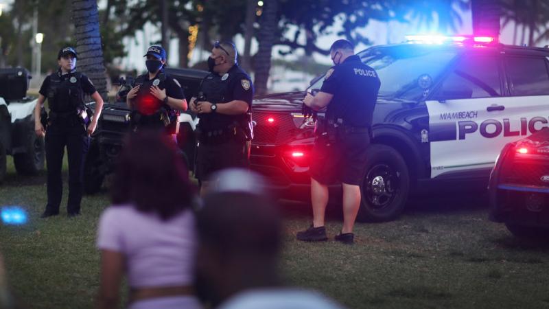 Miami Beach police watch people along Ocean Drive on March 19, 2021