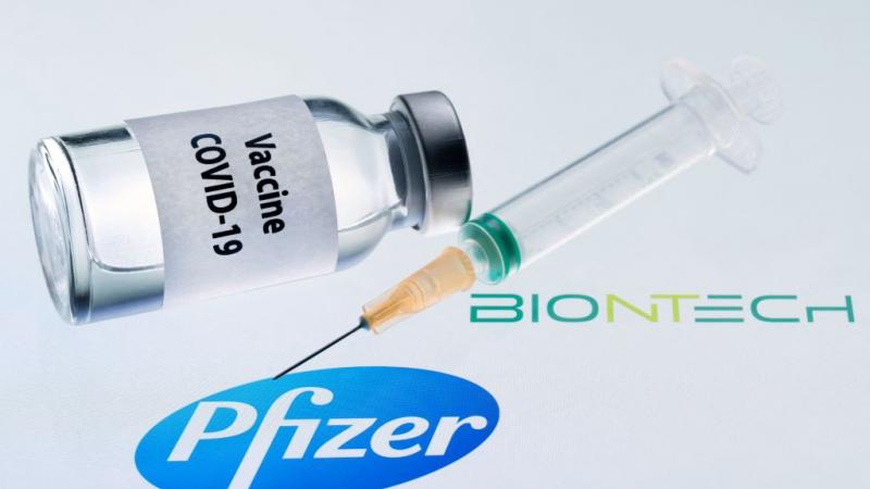 Illustration picture of bottle and syringe next to Pfizer and BioNTech logos