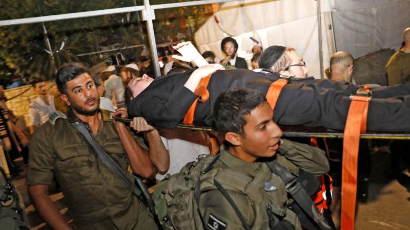 Members of Israeli security move the wounded after collapse of bleachers
