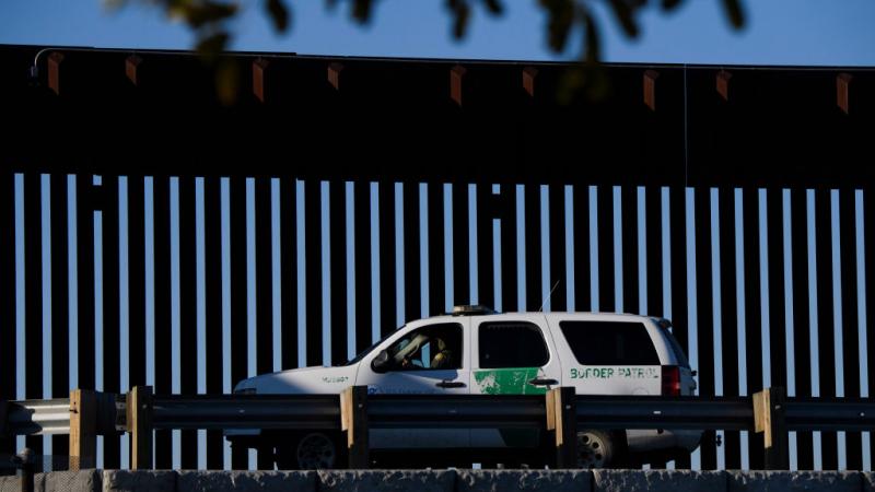 US Border Patrol Agent sits in vehicle along border wall in February 2021