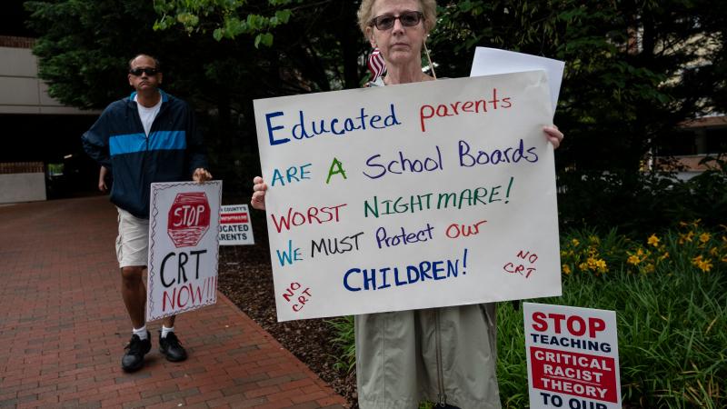 People hold up signs during a rally against "critical race theory" (CRT) being taught in schools at the Loudoun County Government center in Leesburg, Virginia on June 12, 2021.