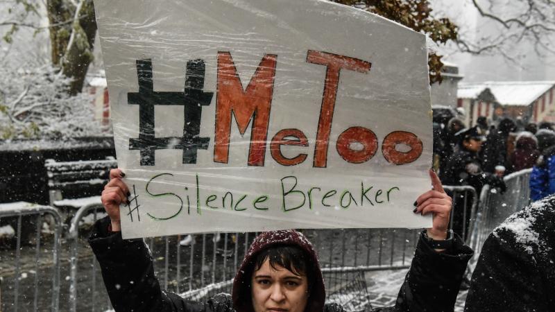 People carry signs addressing the issue of sexual harassment at a #MeToo rally outside of Trump International Hotel on December 9, 2017 in New York City.