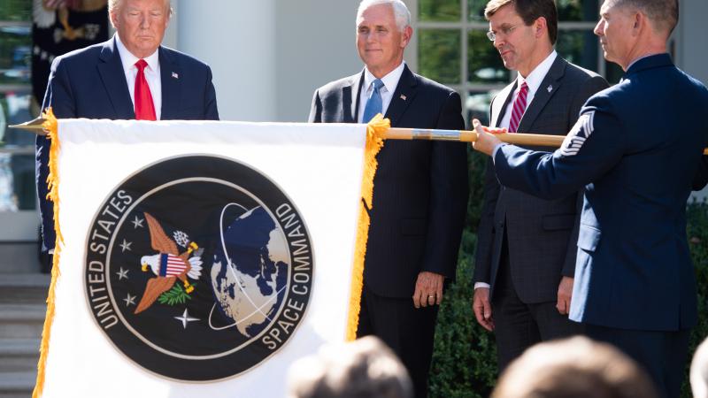 A member of the US military unfurls the new US Space Command flag alongside US President Donald Trump, US Vice President Mike Pence (2nd L) and US Secretary of Defense Mark Esper during an event establishing the US Space Command in the Rose Garden of the White House in Washington, DC, August 29, 2019.