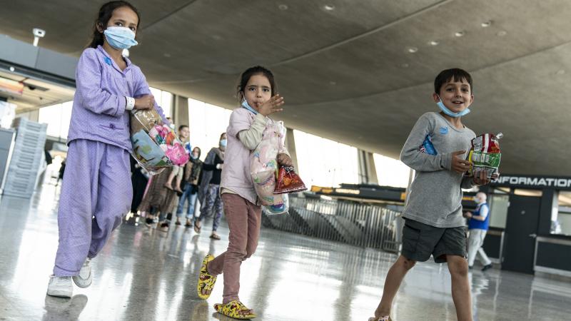 Afghan children eat Doritos and walk to a bus that will take them to a refugee processing center at Dulles International Airport on August 24, 2021 in Dulles, Virginia.