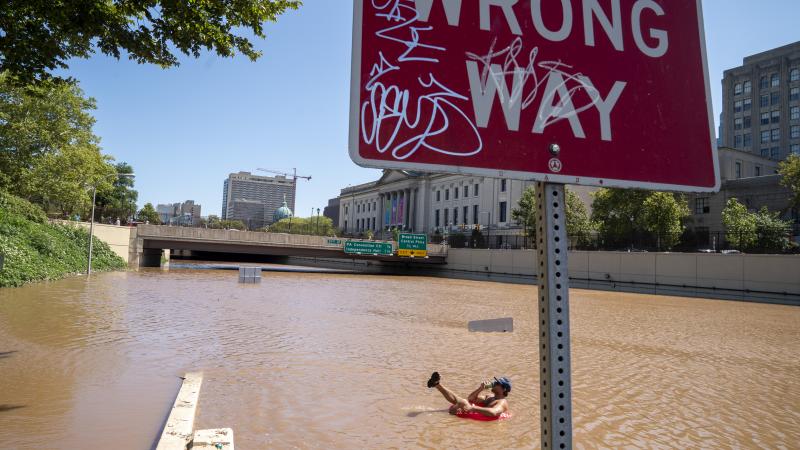 Austin Ferdock drinks a beer while floating in floodwater that continues to rise over the submerged Vine Street Expressway, Interstate 676, following a huge storm caused by the remnants of Hurricane Ida on September 2, 2021 in Philadelphia, Pennsylvania.