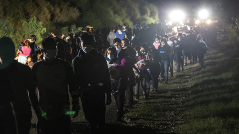 Immigrants walk towards transport busses to a processing center from a U.S. Border Patrol checkpoint on August 14, 2021 in Roma, Texas.