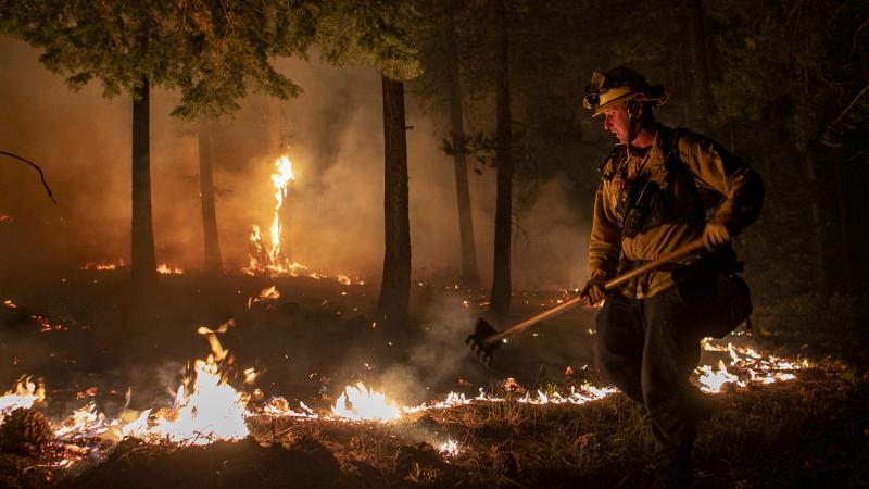 Cal Fire's Brad LaForce keeps a check on the Caldor Fire burning near homes in South Lake Tahoe, Calif., Monday evening, Aug. 30, 2021.