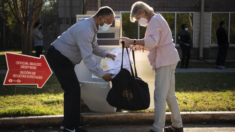 Election officials collect ballots from a drop box on the last day of early voting in Georgia at the Lenora Park Gym in Snellville, Ga., on Friday, October 30, 2020.