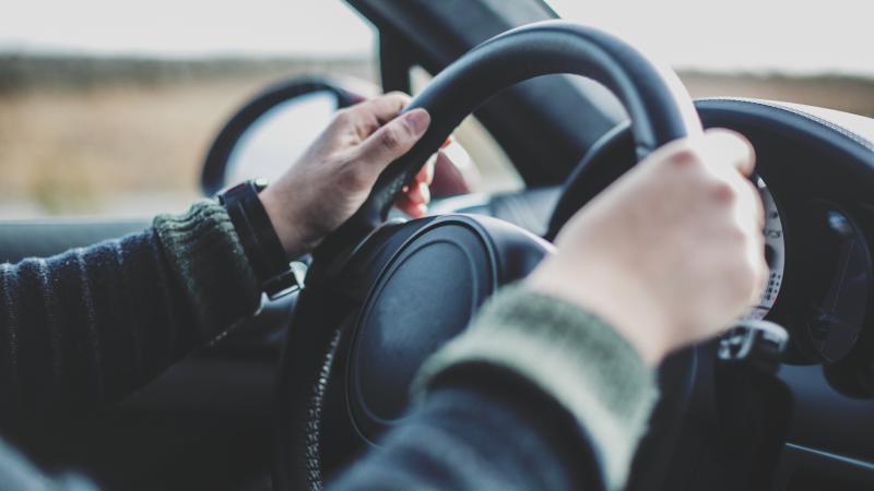 A driver places their hands on the steering wheel.