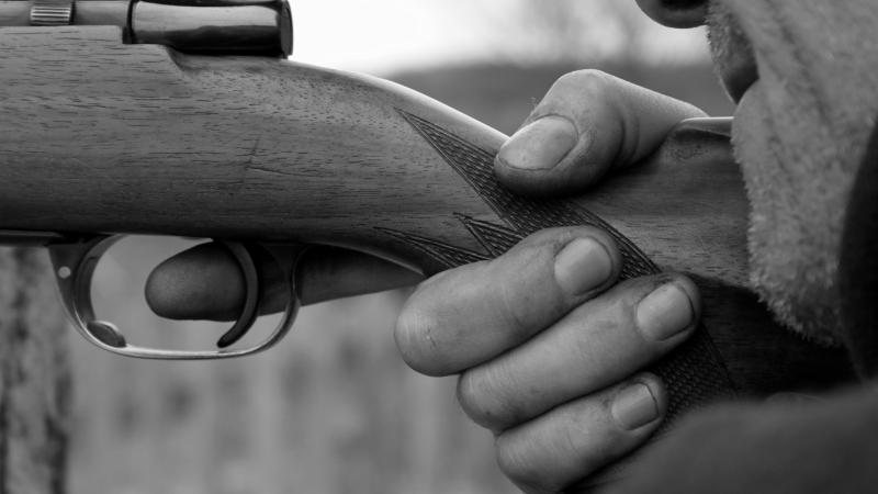 A man holds a rifle poised to shoot