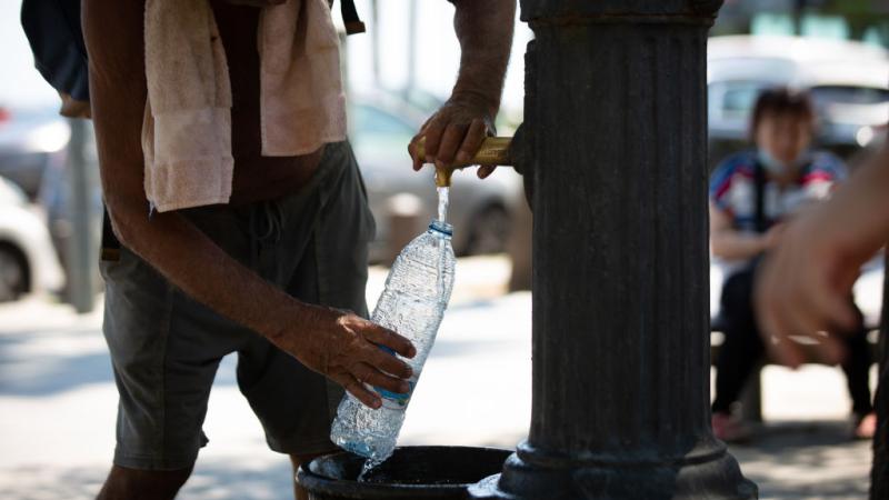 A man refills a water bottle in Barcelona, Spain, during a heat wave, Jul. 13