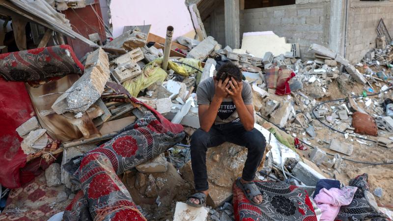 A Palestinian youth reacts as he sits on the rubble of a destroyed home following an Israeli counter-strike in the Gaza Strip 