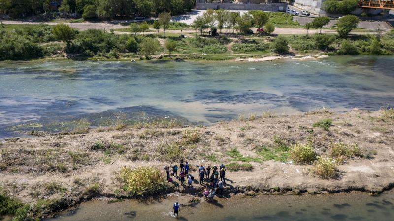 Immigrants cross over an island in the Rio Grande from Mexico into the United States on September 28, 2023 in Eagle Pass, Texas. A surge of asylum seeking migrants crossing the U.S. southern border has put pressure on U.S. immigration authorities, reaching record levels in recent weeks. 