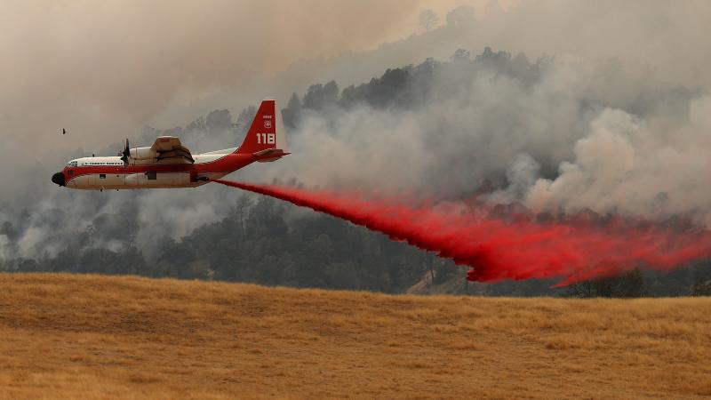Plane flying above field putting out fire