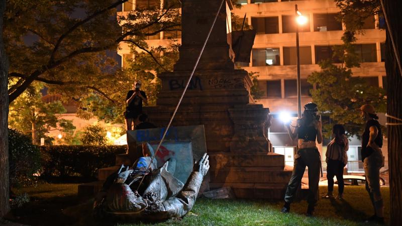 People stand around the statue of Confederate general Albert Pike after it was toppled by protesters at Judiciary square in Washington, DC on late June 19, 2020