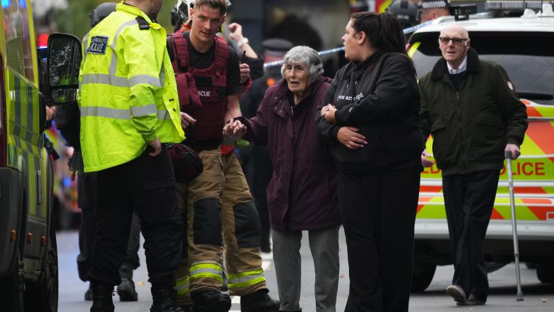 Police and emergency responders help an elderly woman near the Heaton Park Hebrew Congregation Synagogue, where multiple were injured after stabbing and car attack on Yom Kippur, on October 2, 2025 in the Crumpsall suburb of Manchester, England