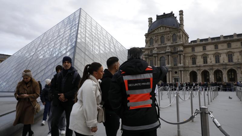 A security guard stands in front of the Pyramide du Louvre