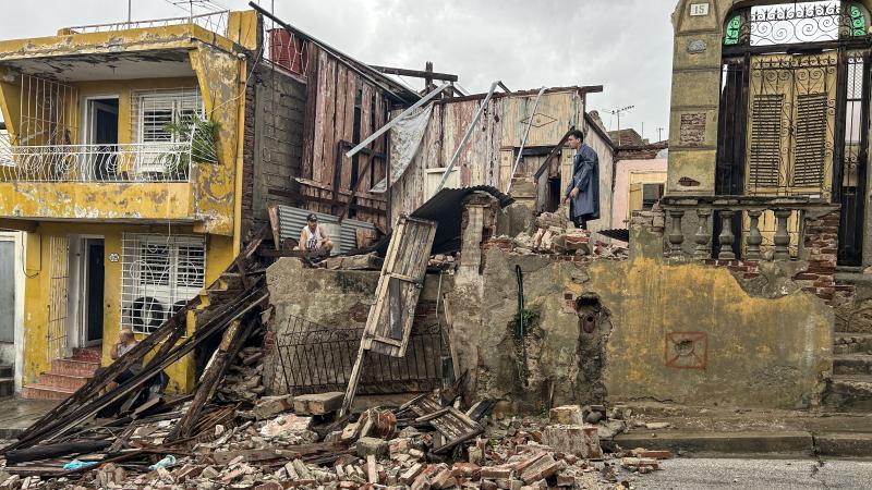 Men salvage belongings from the rubble of her their home after it collapsed during Hurricane Melissa's passage through Santiago de Cuba, Cuba, on October 29, 2025