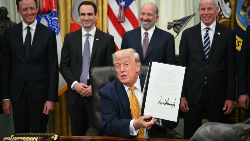US President Donald Trump holds a singed executive order about quantum computing in the Oval Office of the White House in Washington, DC, on June 22, 2026. 