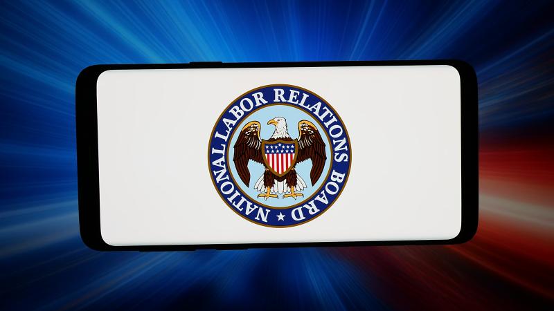 In this photo illustration, the logo of agency National Labor Relations Board (NLRB) is seen displayed on a smartphone in front of an abstract background on a computer screen. 