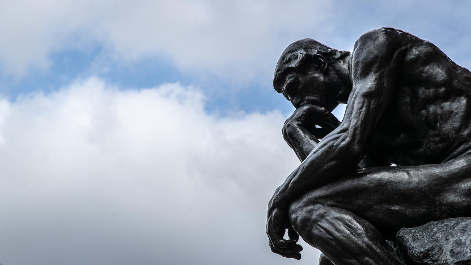 The sculpture "The Thinker" ("Le Penseur") by the sculptor Auguste Rodin can be seen against a cloudy sky.